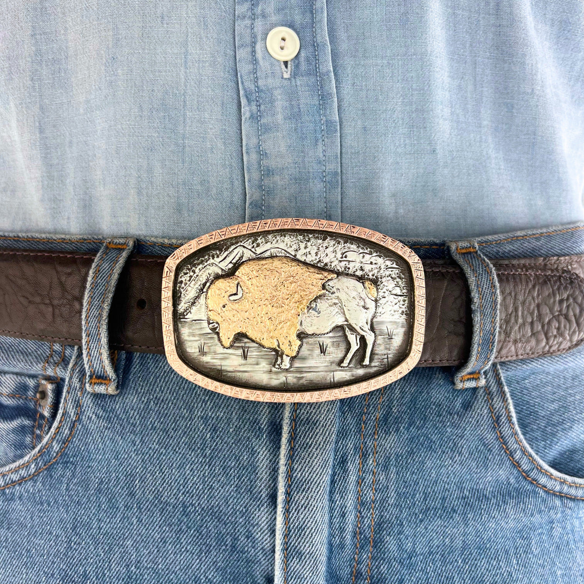 Bohlin 1884+ Buffalo silver and gold belt buckle worn at the waist, showing the two-tone buffalo design and hand-engraved Western landscape.
