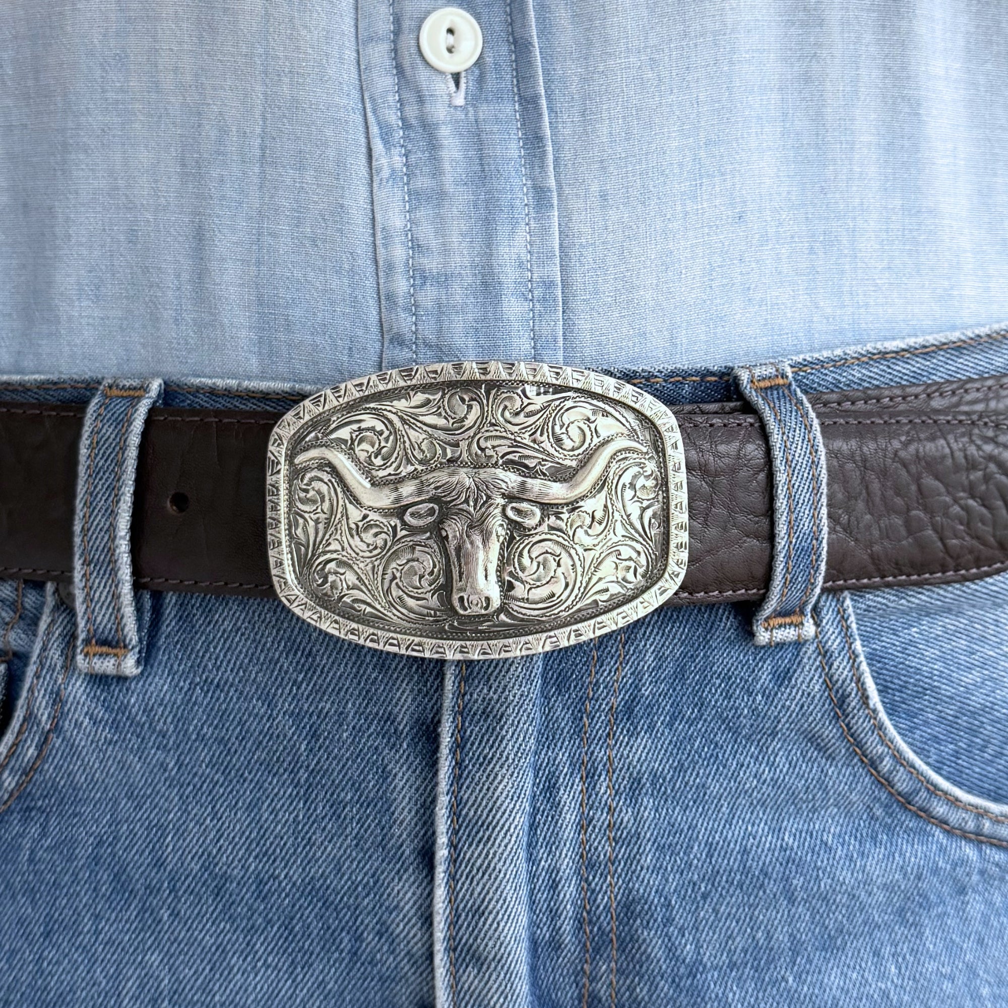 Oval bohlin belt buckle in all silver with longhorn and raised border on brown belt.