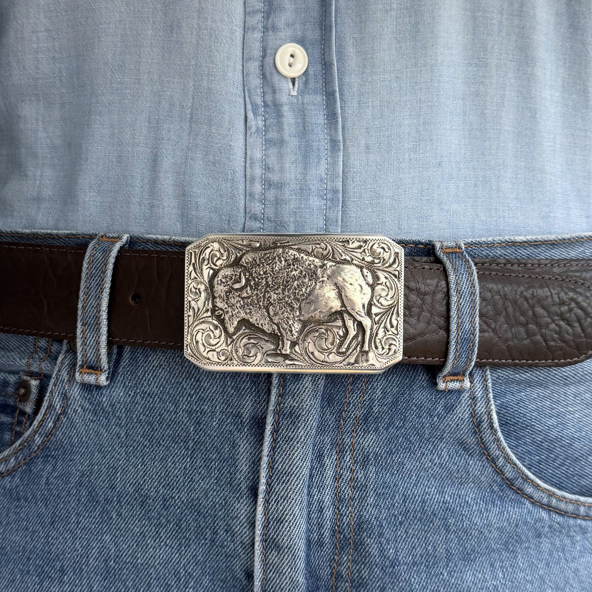 Belt with a detailed buffalo buckle on a brown belt and denim shirt
