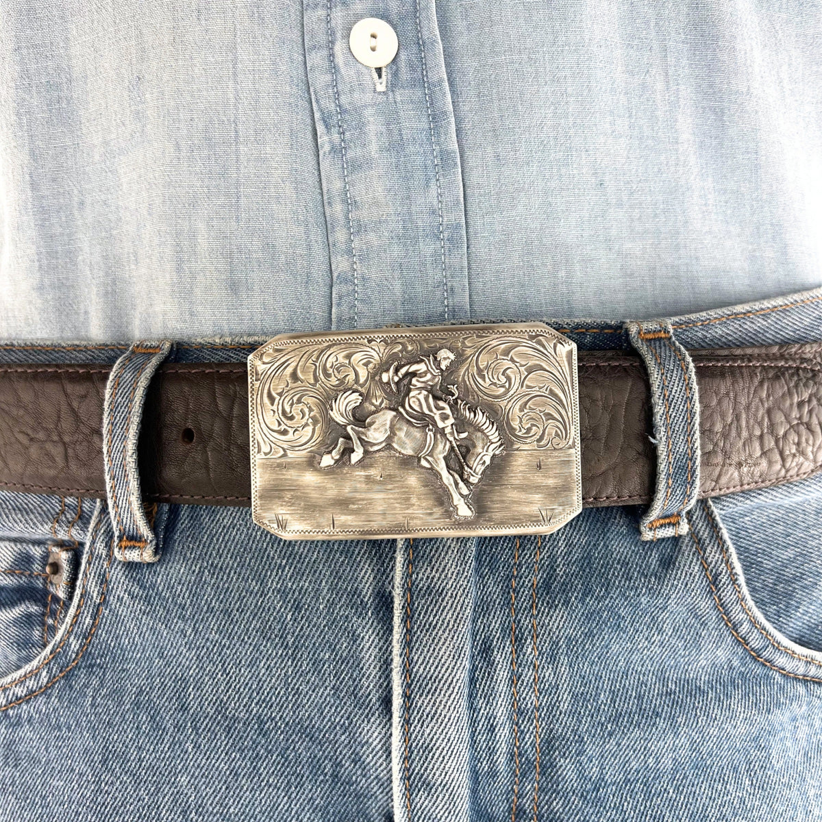 Bohlin 466 Bucking Down sterling silver belt buckle with patina finish worn on a brown leather belt with jeans.