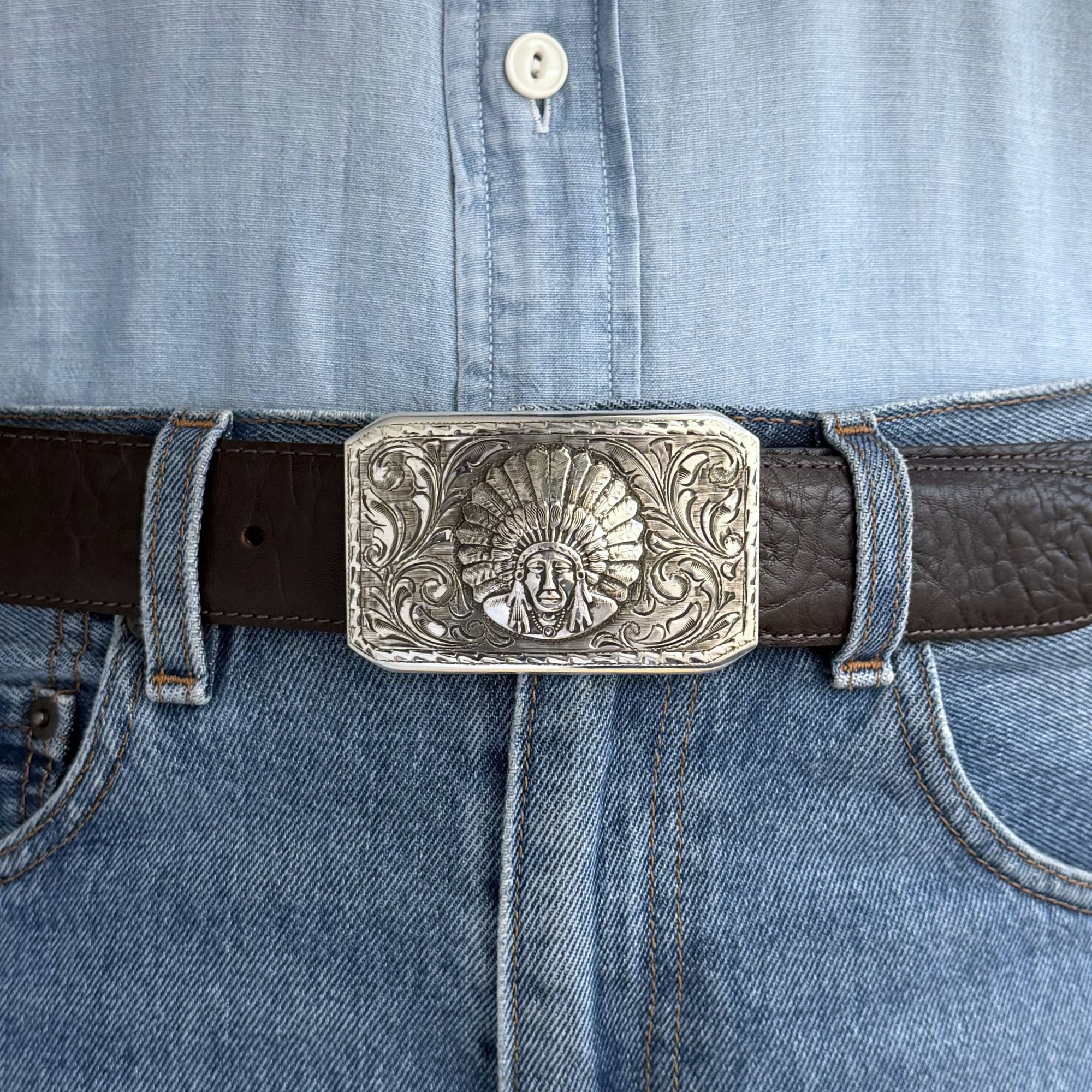 rectangle engraved Bohlin belt buckle with Chief Red Wolf on brown belt. Denim shirt and jeans also in the photo.