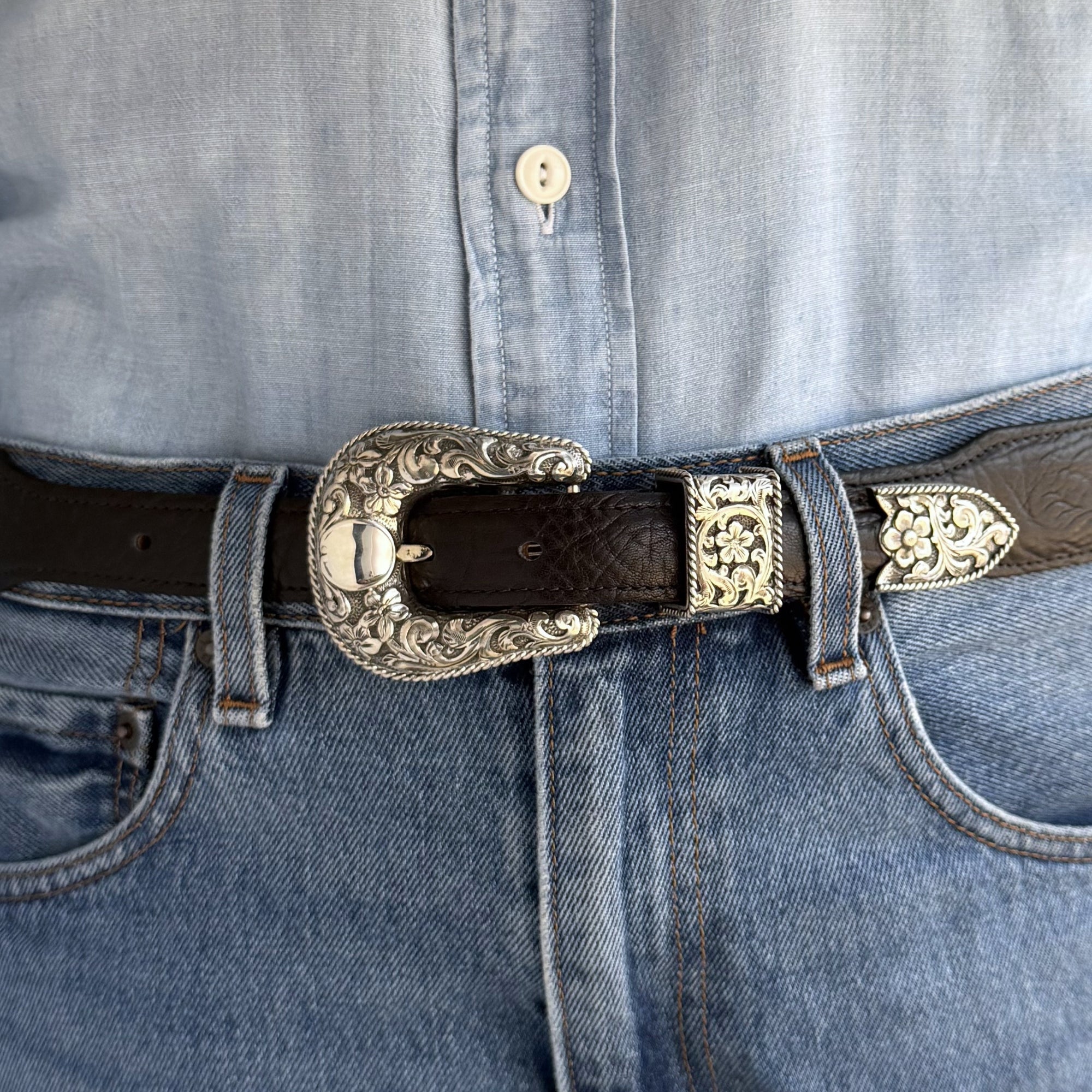 Close-up of a belt with a Bohlin Buckle overlaid scrolls and flowers with a twisted rope edge- all Sterling Silver 
