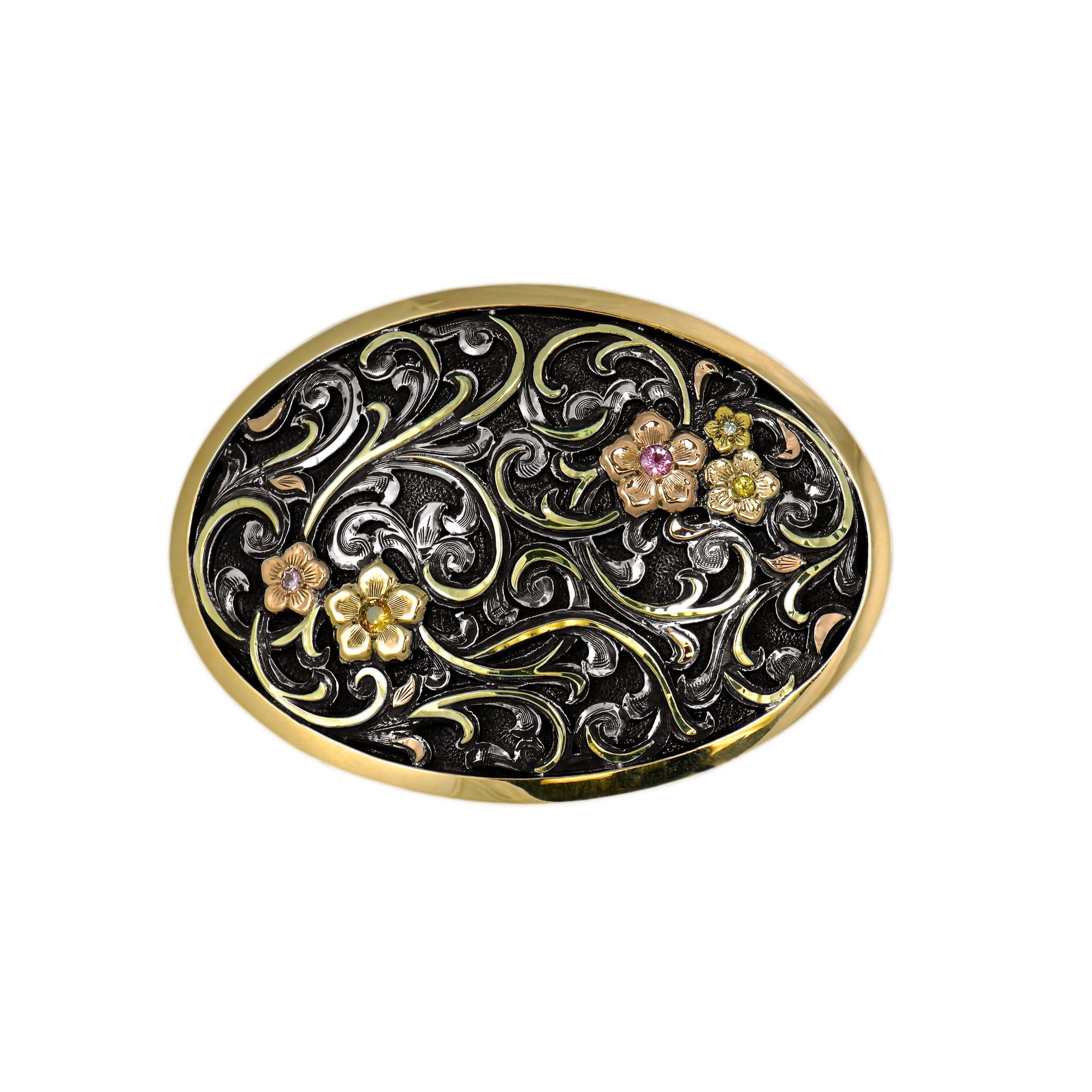 An oval belt buckle featuring an intricate black and gold filigree scrollwork design with three small floral motifs in gold, pink, and green tones, set against a plain white background.