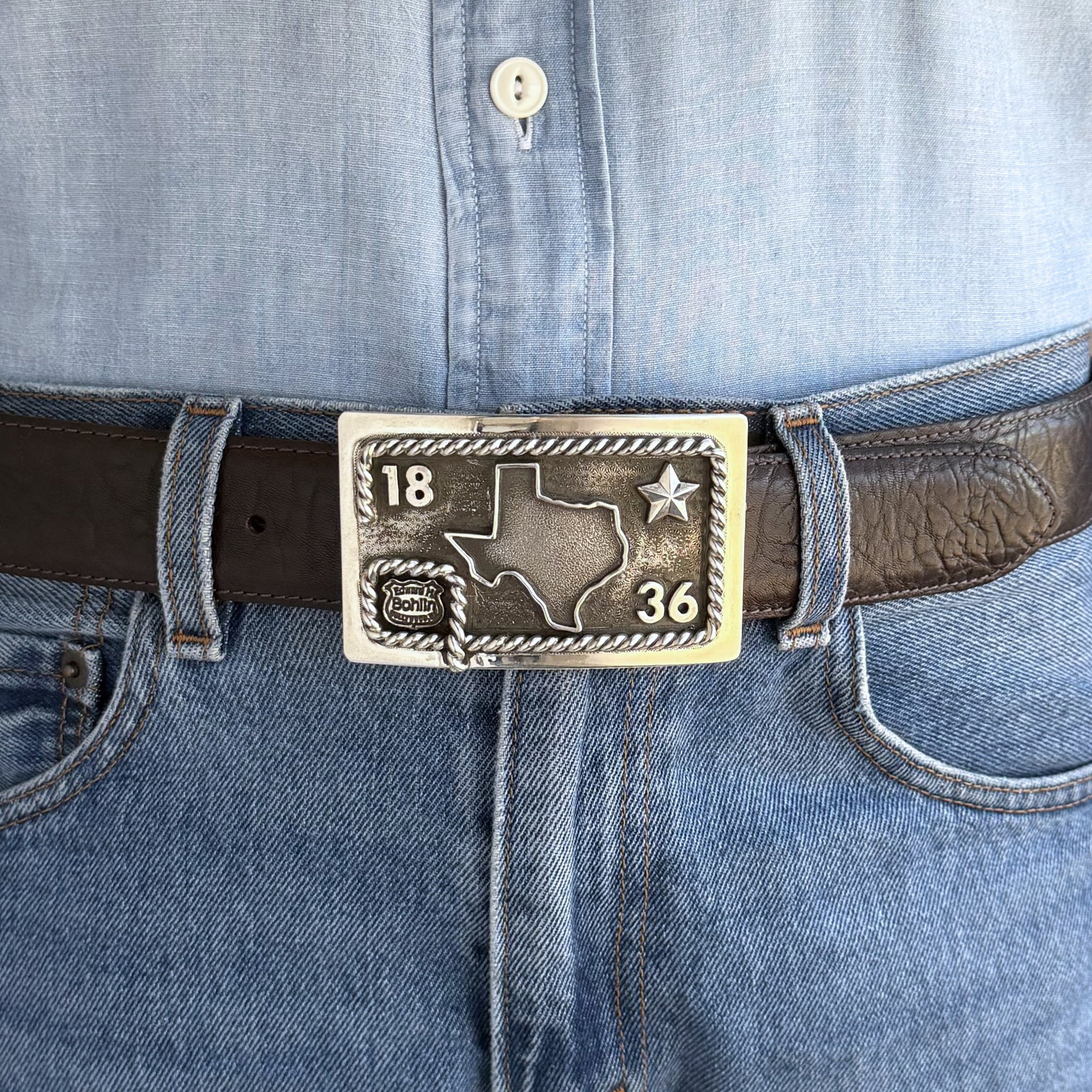 Belt with a Texas-shaped buckle worn on blue jeans
