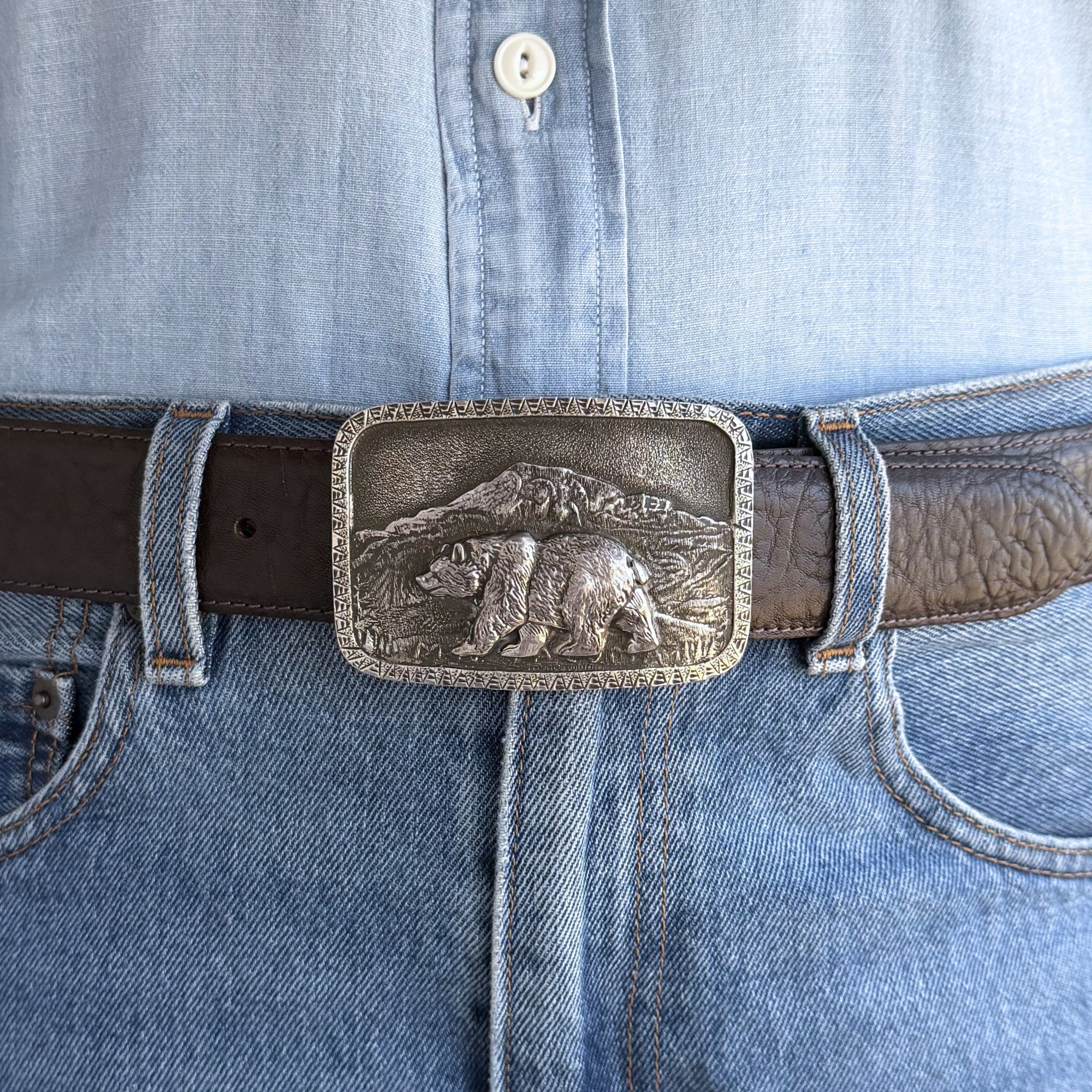 Belt with a bear buckle worn on blue jeans